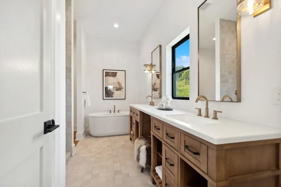 Bathroom with a freestanding tub, white walls and a wood vanity
