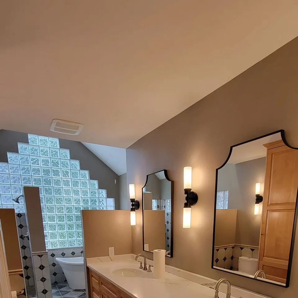 Remodeled bathroom with arched mirrors and sconces