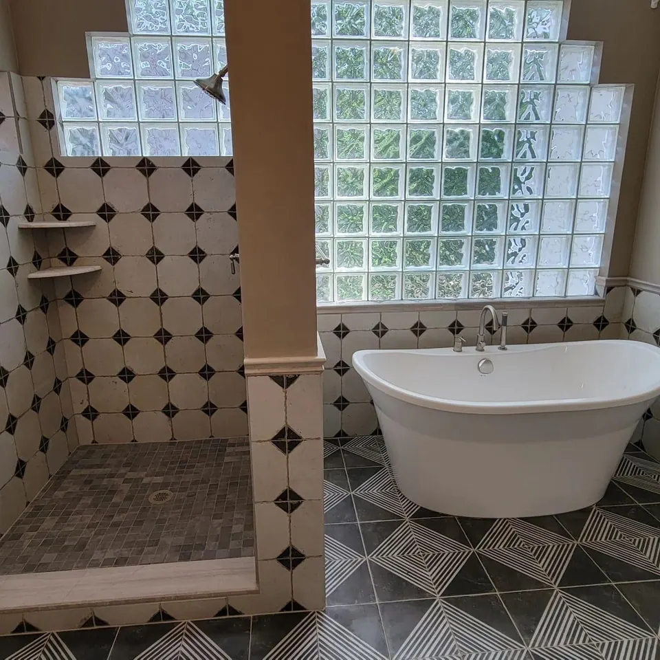 Remodeled bathroom with a glass block window, freestanding tub and patterned tile