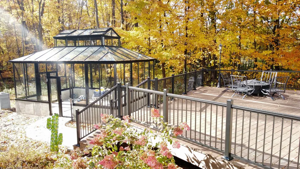 The rebuilt composite deck with black railing and a glass gazebo in fall