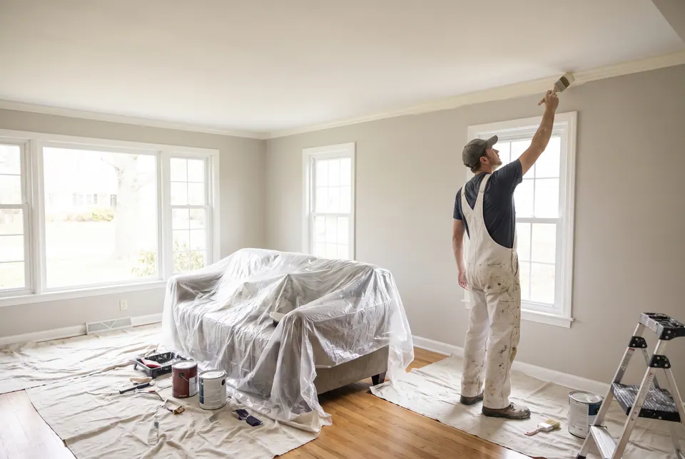 Painter cutting a clean line where a wall meets the ceiling with an angled brush