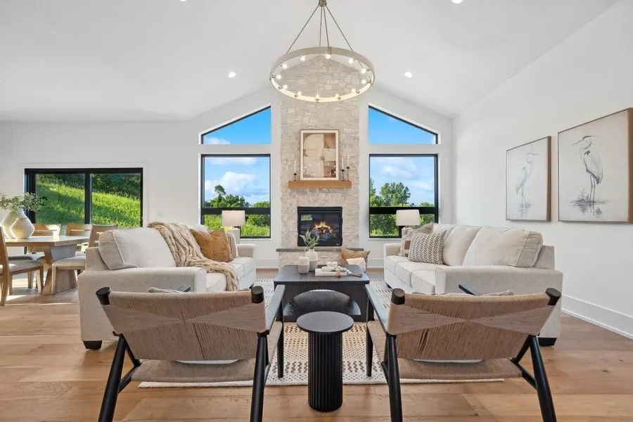 Living room with a stone fireplace, vaulted ceiling and white painted walls