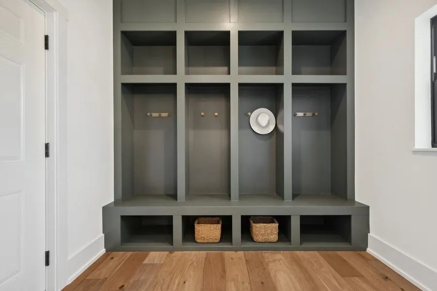 Mudroom lockers painted deep green with a wood bench